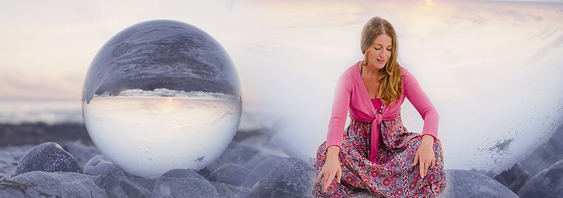 Mirja sitzt und im Hintergrund sieht man eine Glaskugel die das Meer und den Strand spiegelt